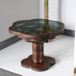 A round, floral-inspired coffee table with a layered walnut design and a tempered glass top, placed in a modern living room setting.