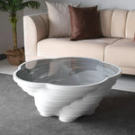 A modern, multi-tiered white coffee table with a glass top, designed by Papella Design, positioned in a living room setting.